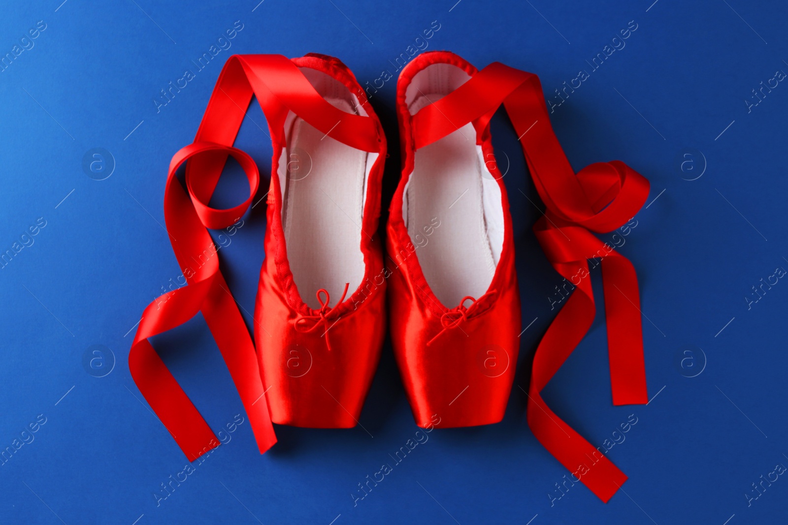 Photo of Pair of beautiful red pointe shoes on blue background, top view