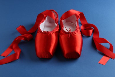 Photo of Pair of beautiful red pointe shoes on blue background