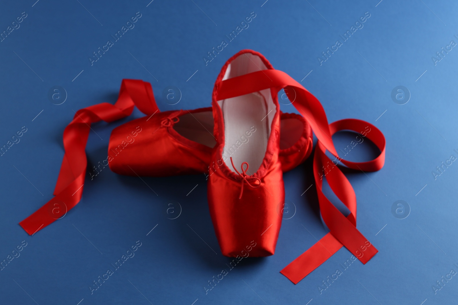 Photo of Pair of beautiful red pointe shoes on blue background