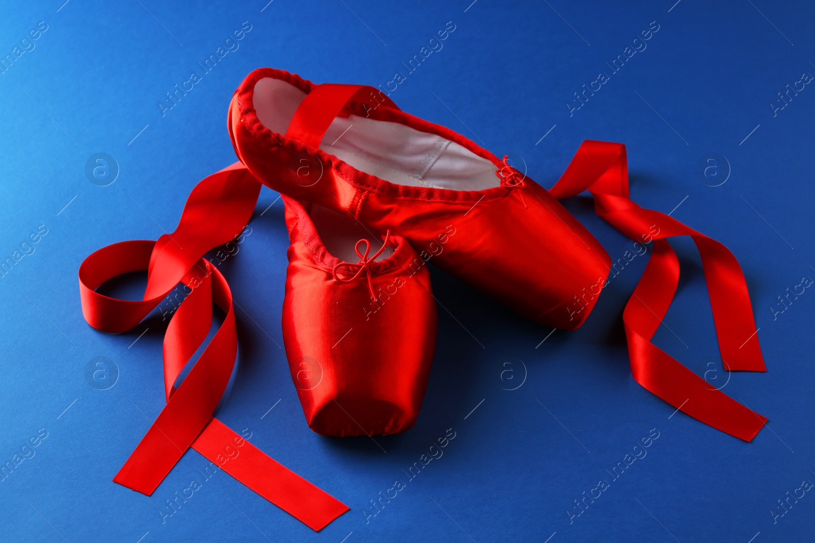 Photo of Pair of beautiful red pointe shoes on blue background