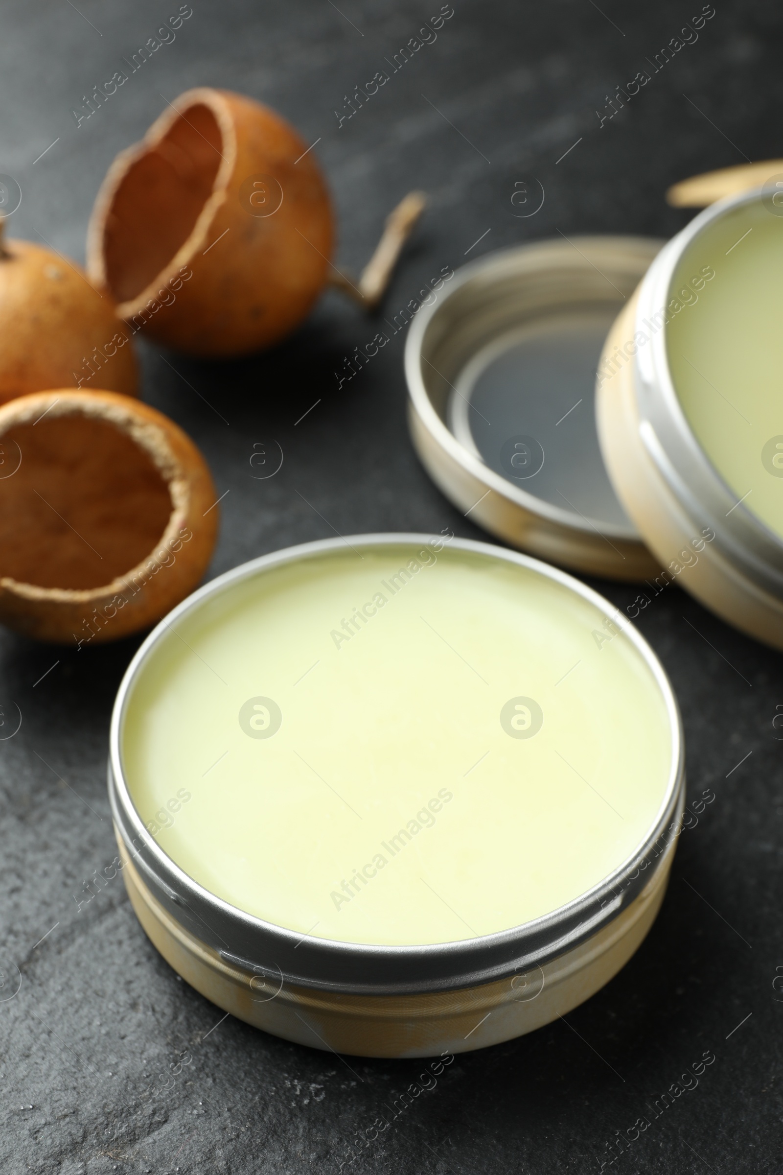 Photo of Natural solid perfume and dry fruit peels on black table, closeup