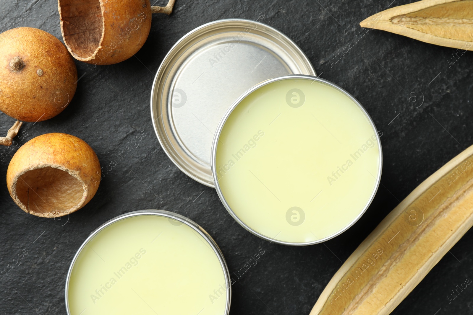 Photo of Natural solid perfume and dry fruit peels on black table, top view