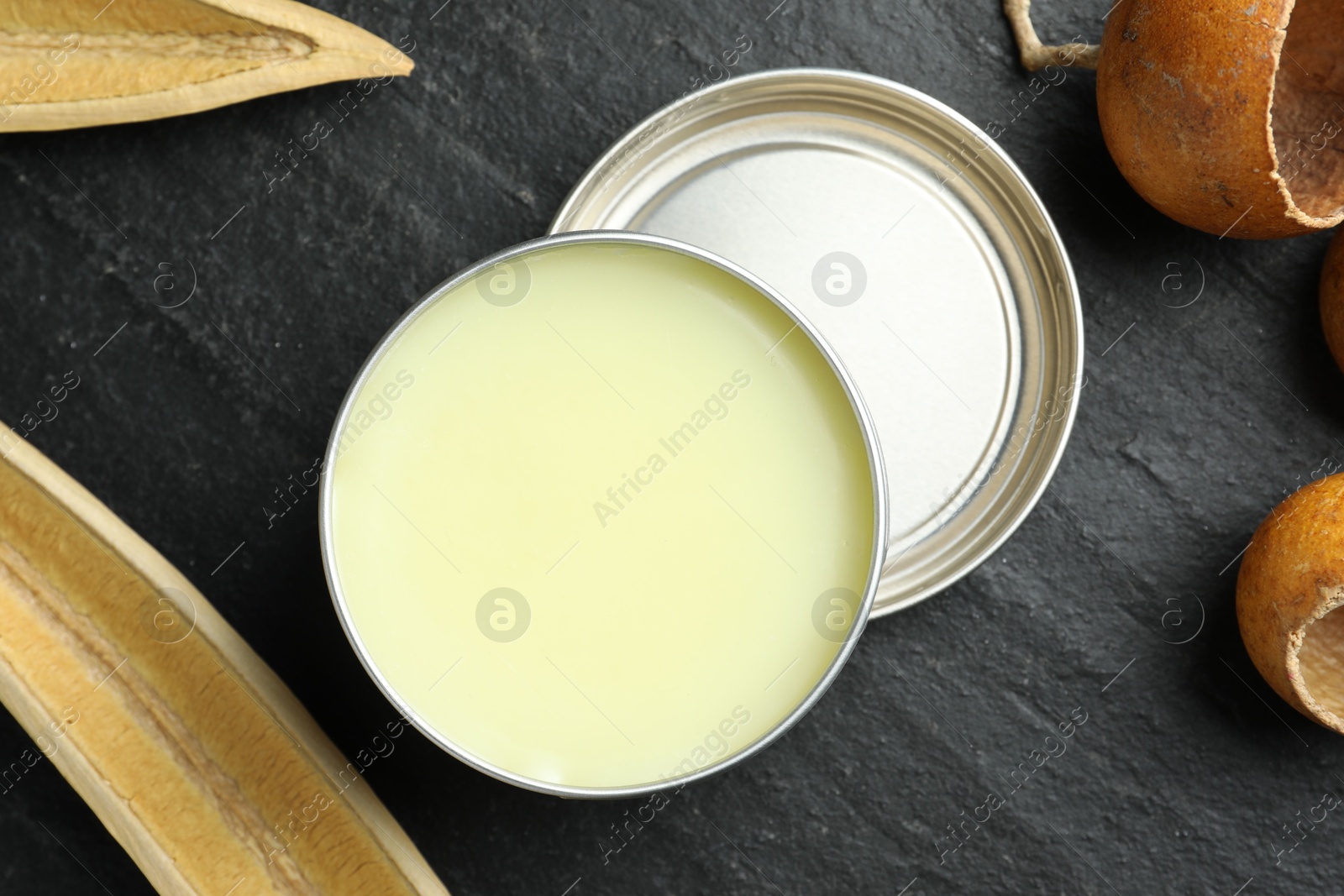 Photo of Natural solid perfume and dry fruit peels on black table, top view