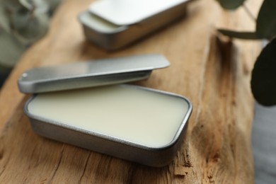 Photo of Natural solid perfume in containers on wood, selective focus