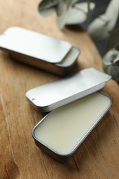 Photo of Natural solid perfume in containers on wood, selective focus