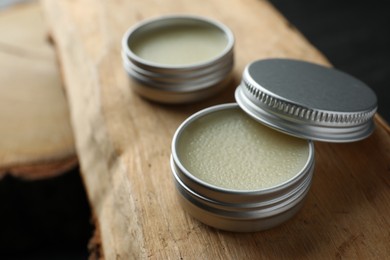 Photo of Natural solid perfume in containers on wood, selective focus