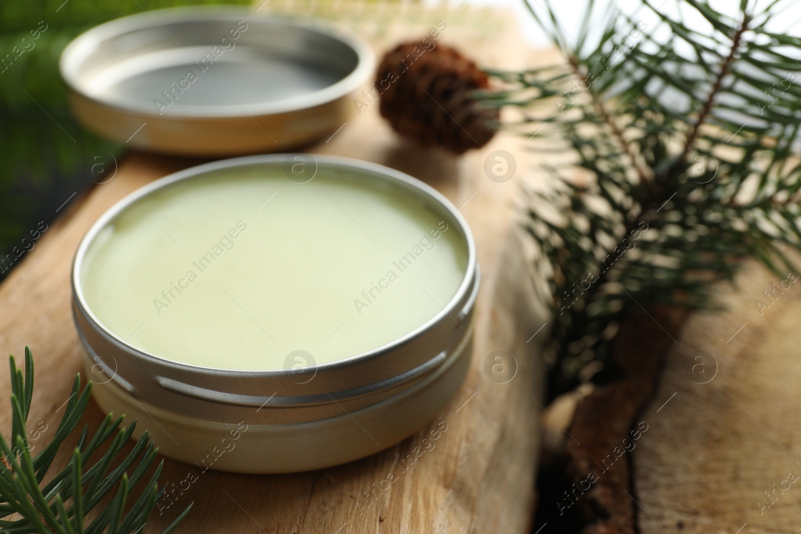 Photo of Natural solid perfume and fir twigs on wood, closeup