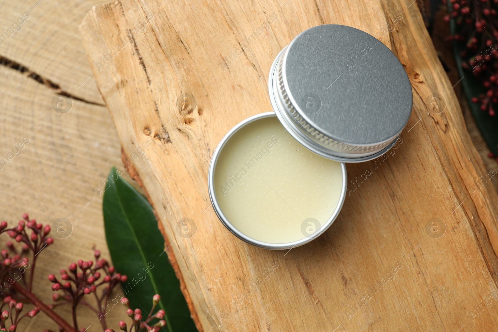 Photo of Natural solid perfume and skimmia plant on wood, top view. Space for text