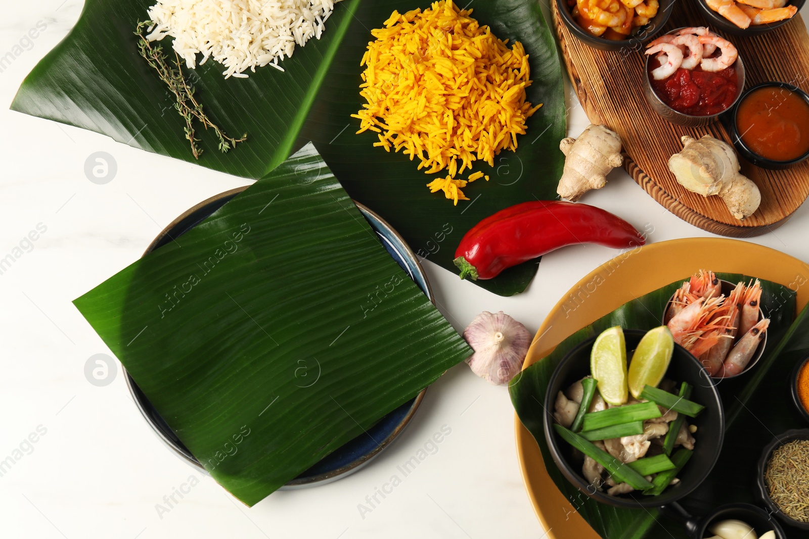 Photo of Cut banana leaves with different food on white table, flat lay. Healthy eco serving