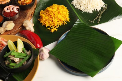 Photo of Cut banana leaves with different food on white table, closeup. Healthy eco serving