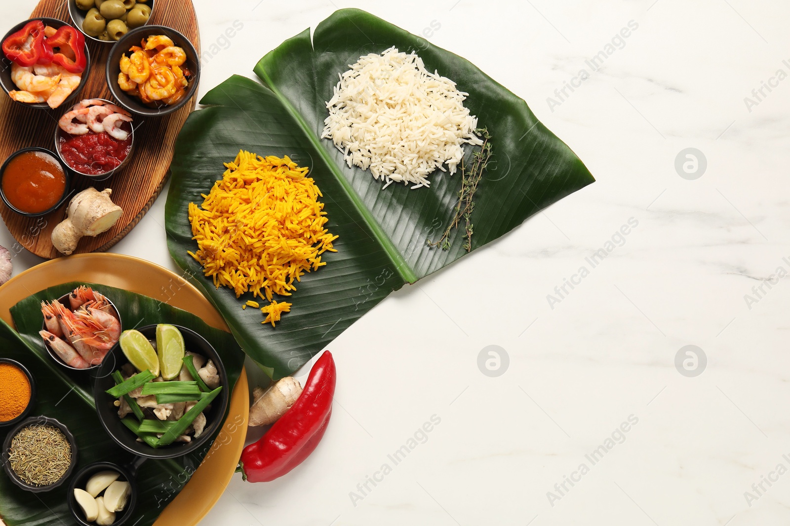 Photo of Cut banana leaves with different food, spices and sauce on white marble table, flat lay. Space for text