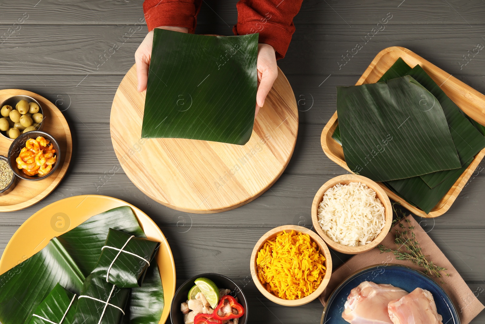 Photo of Woman with banana leaf at wooden table with different products, top view. Healthy eco serving