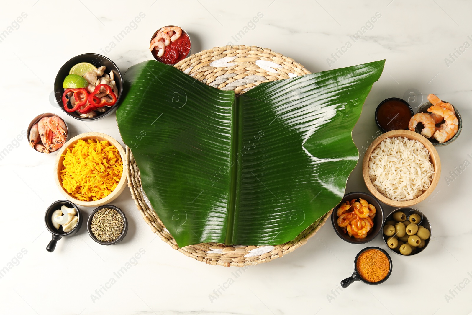 Photo of Piece of banana leaf, different food and spices on white table, flat lay. Healthy eco serving