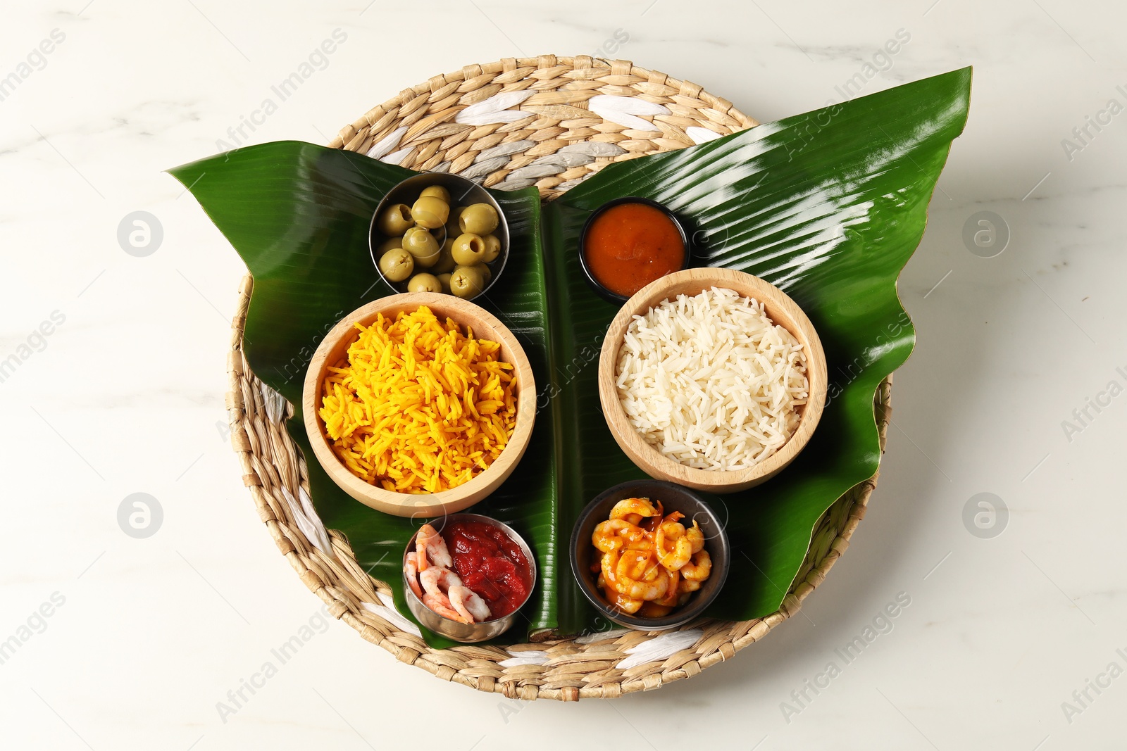 Photo of Piece of banana leaf with different food and sauce on white table, top view. Healthy eco serving