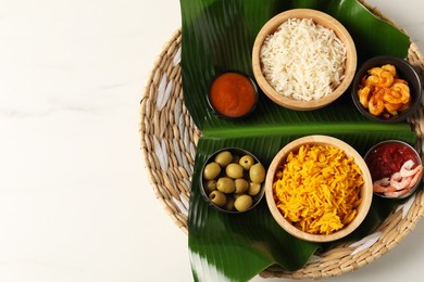 Photo of Piece of banana leaf with different food and sauce on white table, top view. Space for text