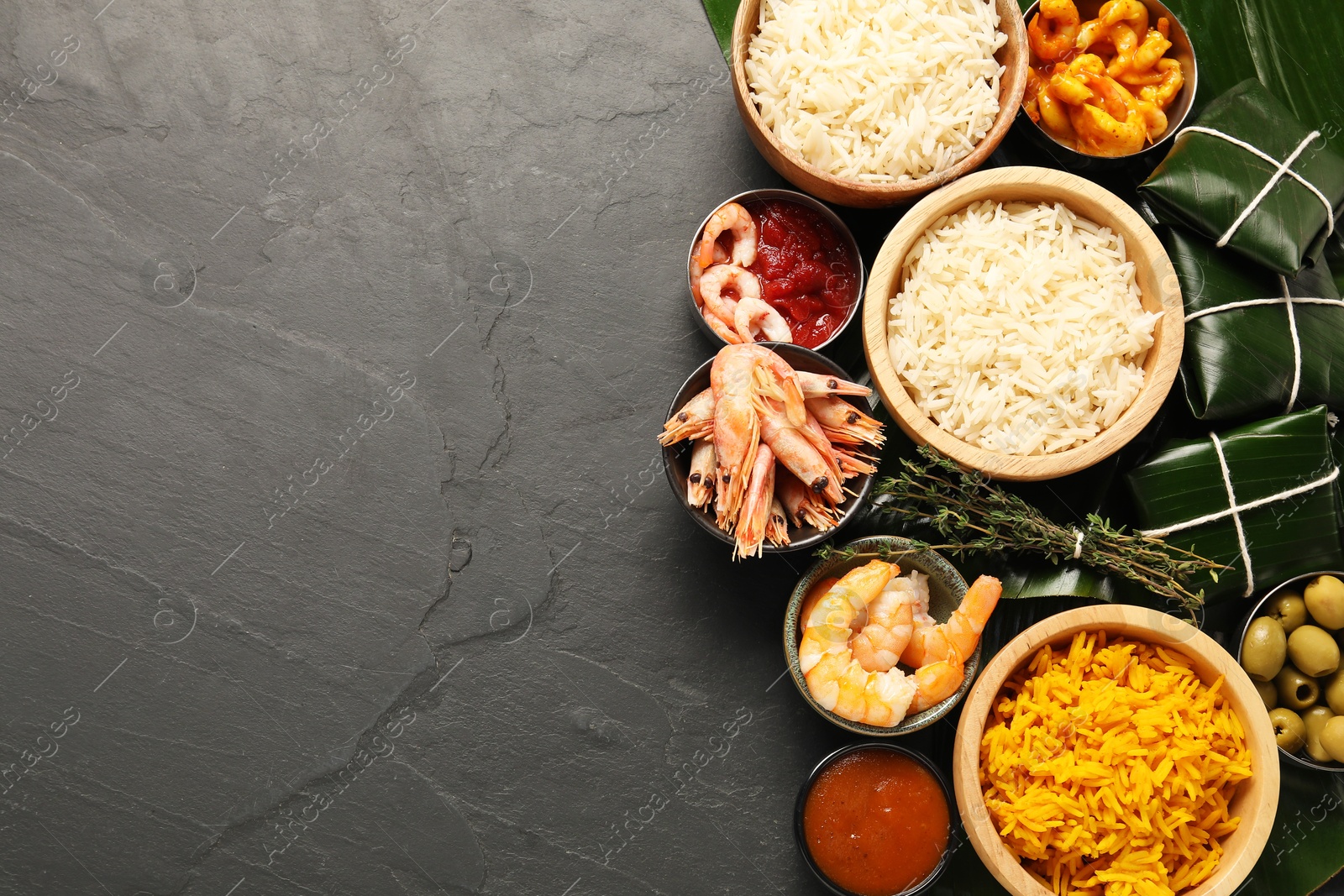 Photo of Cut banana leaves with different food and sauce on dark textured table, flat lay. Space for text