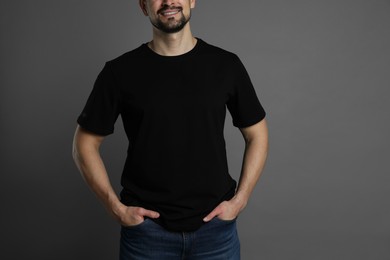 Photo of Man in blank black t-shirt on grey background, closeup. Mockup for design