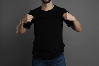 Photo of Man in blank black t-shirt on grey background, closeup. Mockup for design