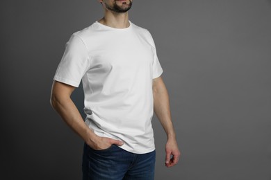 Photo of Man in blank white t-shirt on grey background, closeup. Mockup for design