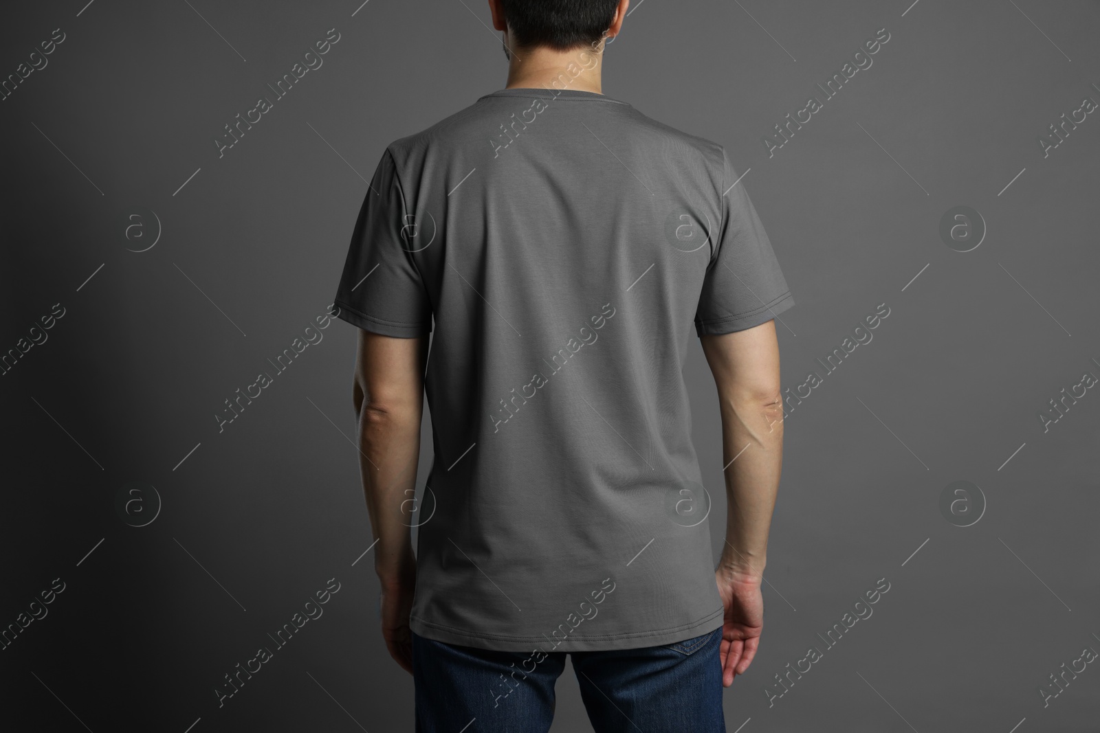 Photo of Man in blank t-shirt on grey background, back view. Mockup for design