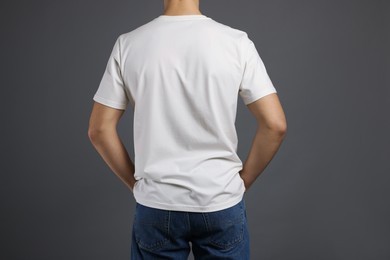 Photo of Man in stylish t-shirt on grey background, back view. Mockup for design