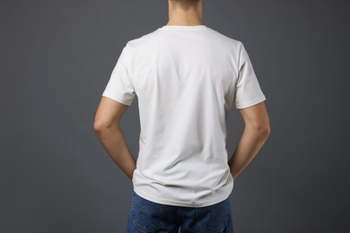 Photo of Man in stylish t-shirt on grey background, back view. Mockup for design