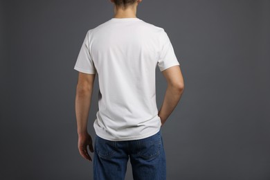 Photo of Man in stylish t-shirt on grey background, back view. Mockup for design