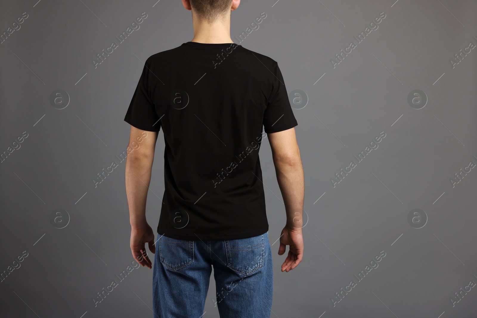 Photo of Man in stylish t-shirt on grey background, back view. Mockup for design