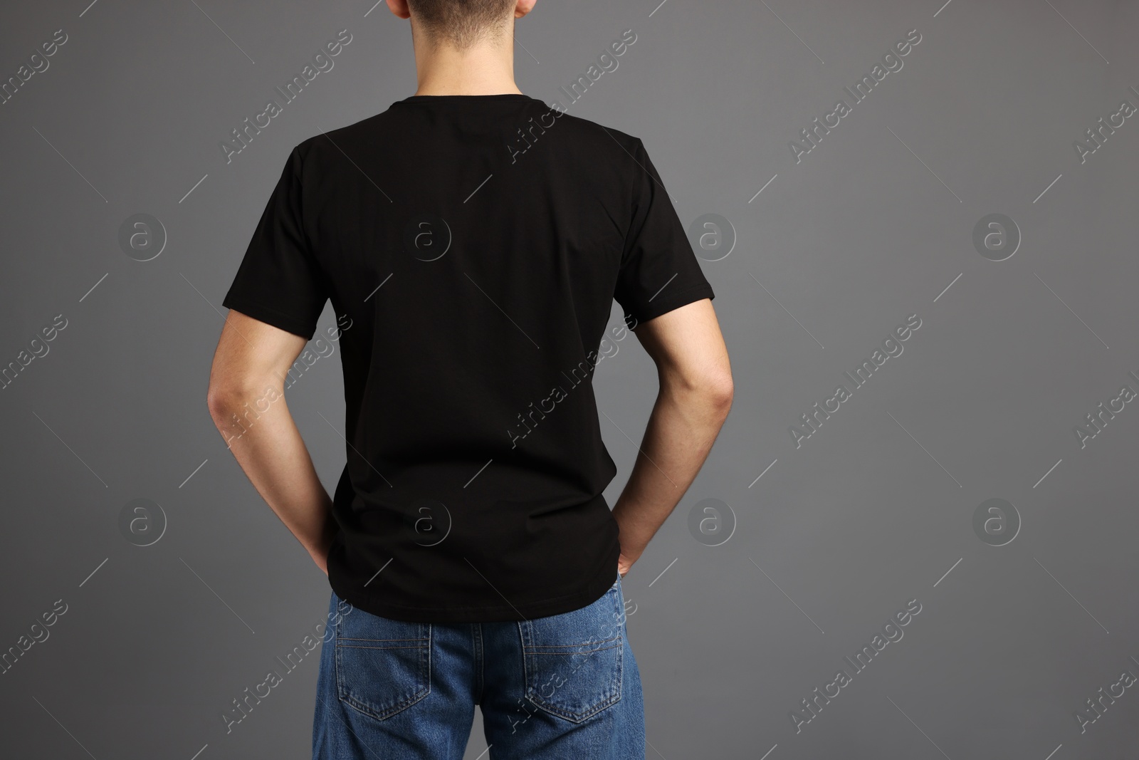 Photo of Man in stylish t-shirt on grey background, back view. Mockup for design