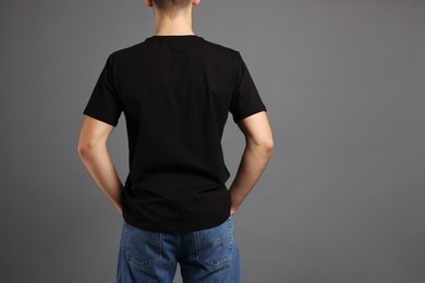 Photo of Man in stylish t-shirt on grey background, back view. Mockup for design