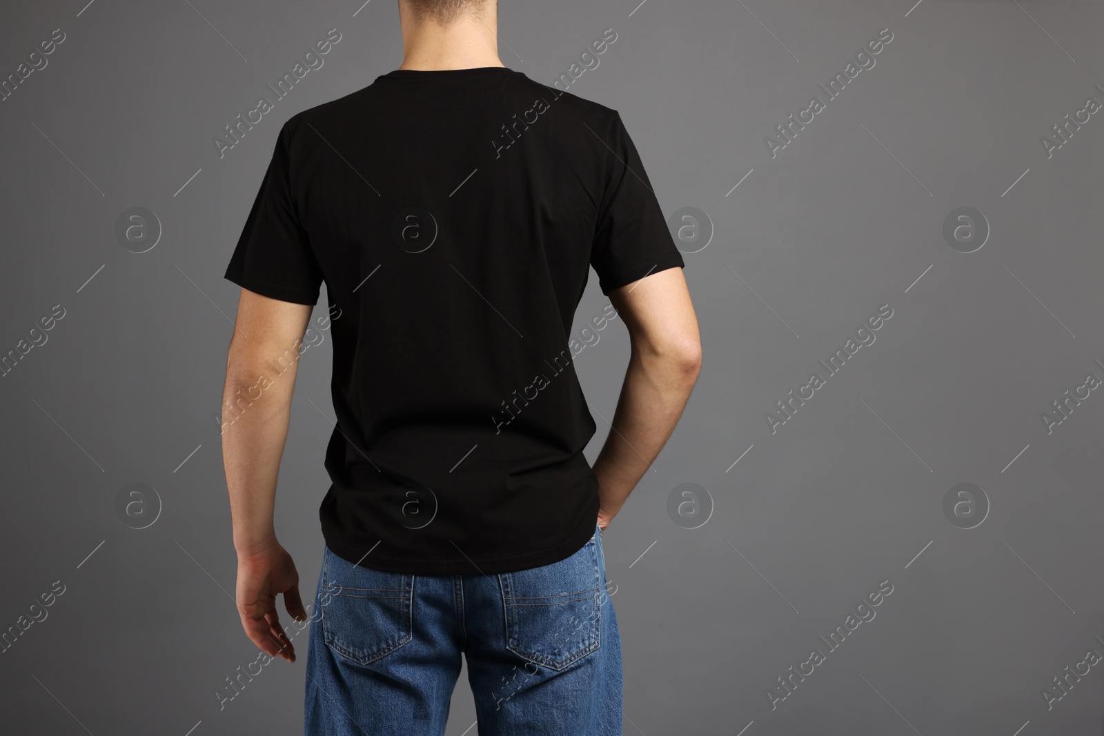 Photo of Man in stylish t-shirt on grey background, back view. Mockup for design