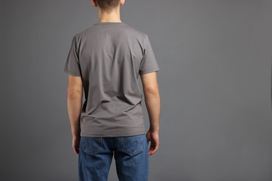 Photo of Man in stylish t-shirt on grey background, back view. Mockup for design