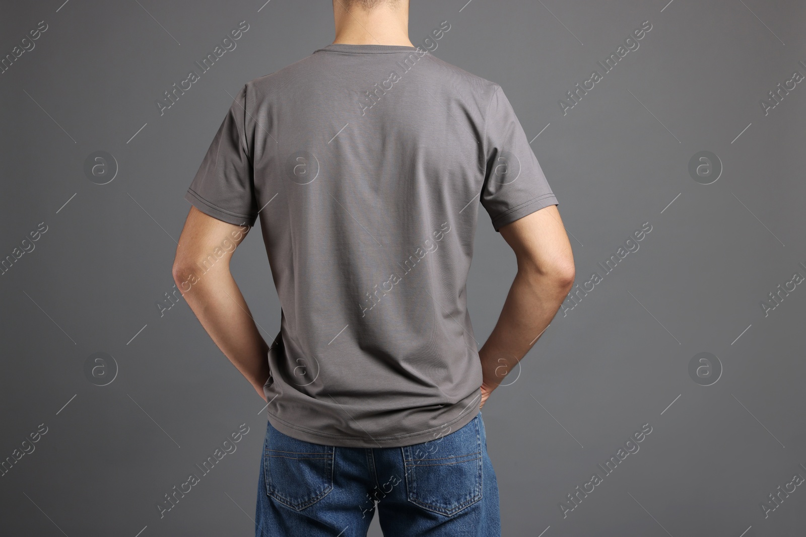 Photo of Man in stylish t-shirt on grey background, back view. Mockup for design