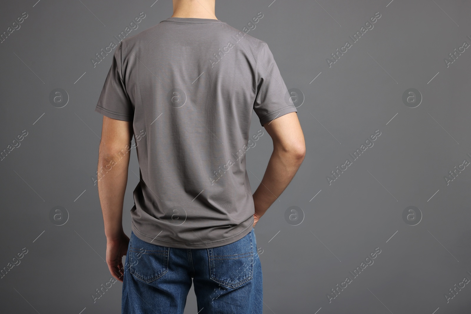 Photo of Man in stylish t-shirt on grey background, back view. Mockup for design