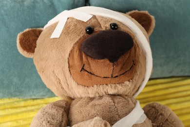 Photo of Cute teddy bear with bandages and adhesive medical plasters on bed