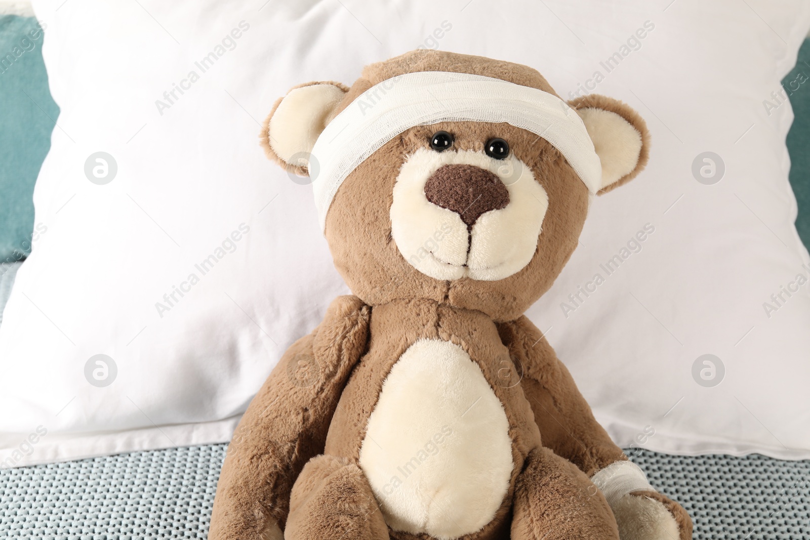 Photo of Cute teddy bear with bandages on bed, top view