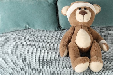 Photo of Cute teddy bear with bandages on bed, top view. Space for text