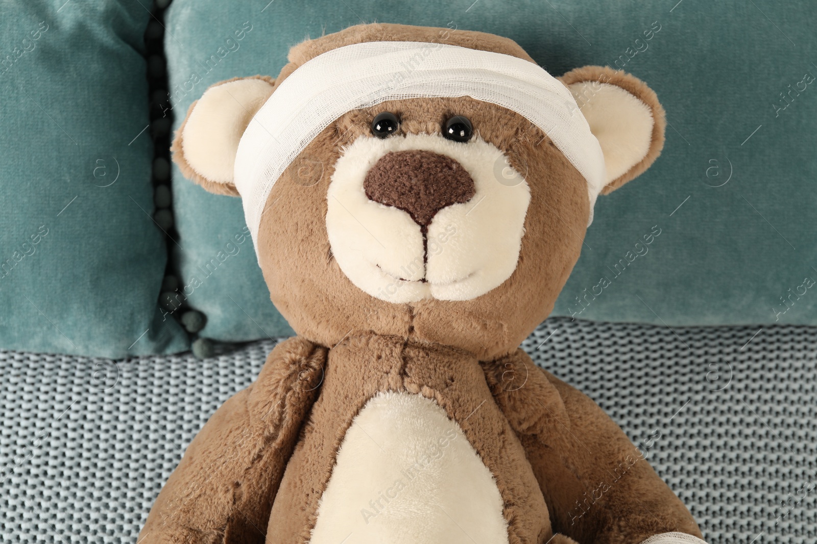 Photo of Cute teddy bear with bandage on bed, top view