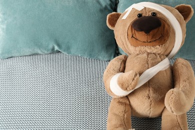 Photo of Cute teddy bear with bandages and adhesive medical plasters on bed, top view. Space for text