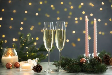 Photo of Delicious champagne in glasses and Christmas decor on marble table against blurred lights