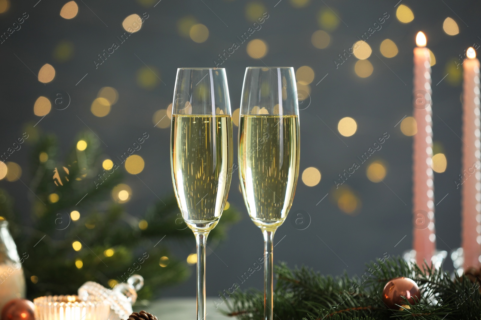 Photo of Delicious champagne in glasses and Christmas decor against blurred lights, closeup