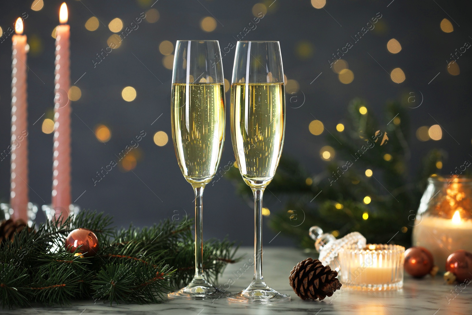 Photo of Delicious champagne in glasses and Christmas decor on marble table against blurred lights, closeup