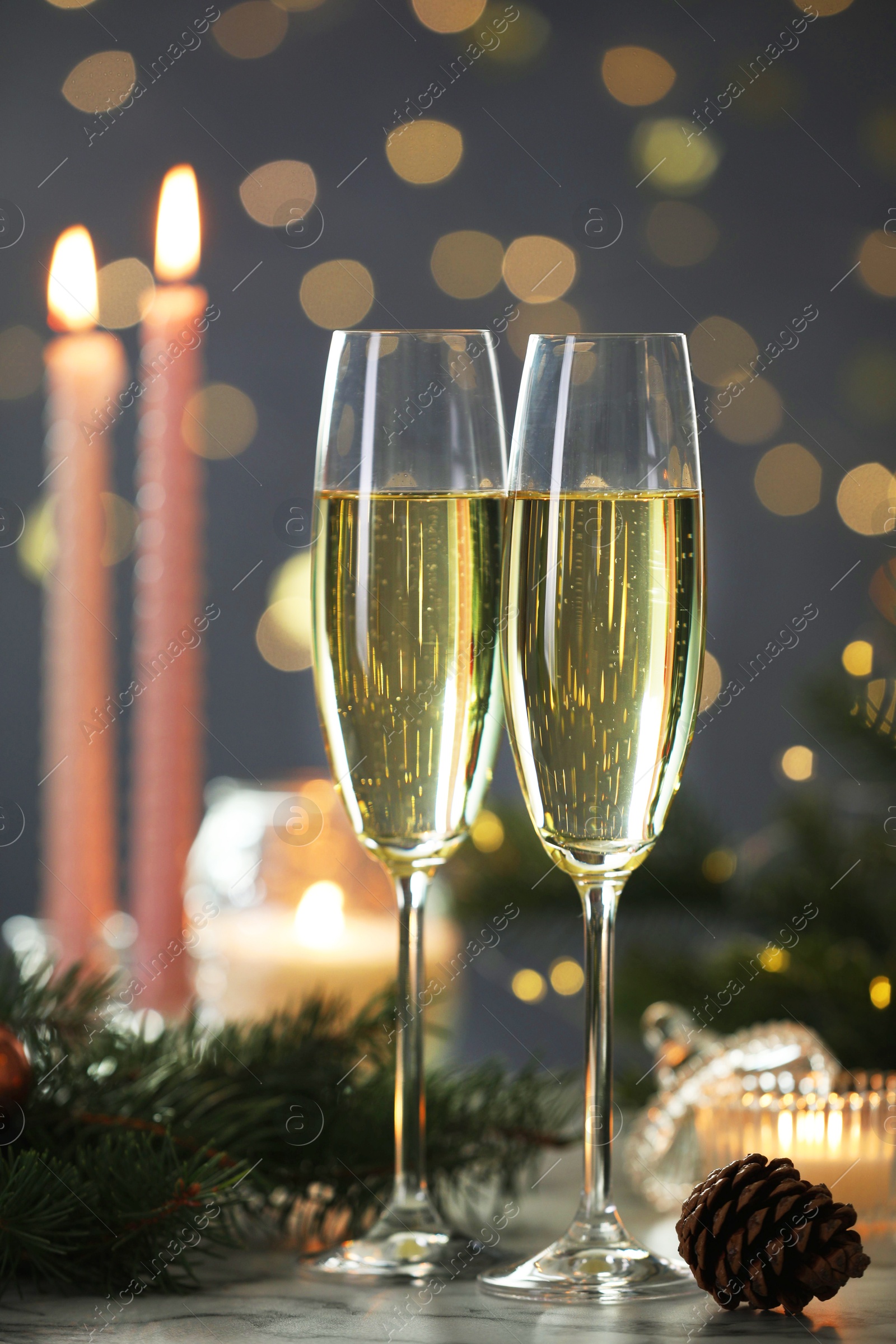 Photo of Delicious champagne in glasses and Christmas decor on marble table against blurred lights, closeup