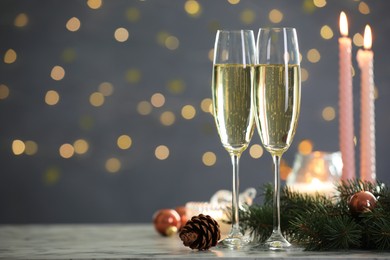 Photo of Delicious champagne in glasses and Christmas decor on marble table against blurred lights, closeup. Space for text