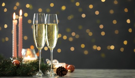 Photo of Delicious champagne in glasses and Christmas decor on marble table against blurred lights, closeup. Space for text