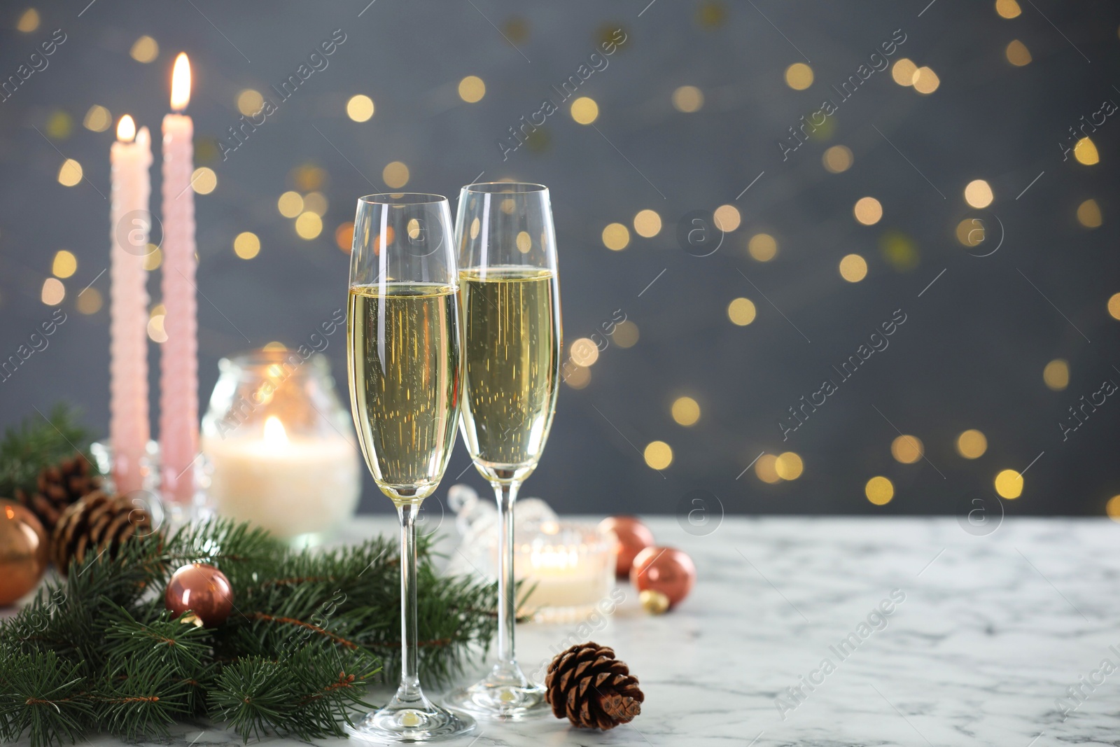 Photo of Delicious champagne in glasses and Christmas decor on marble table against blurred lights, closeup. Space for text