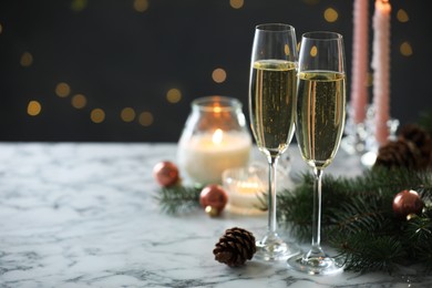 Photo of Delicious champagne in glasses and Christmas decor on marble table against blurred lights, closeup. Space for text