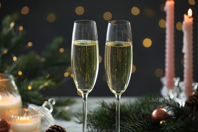 Photo of Delicious champagne in glasses and Christmas decor on table against blurred lights, closeup