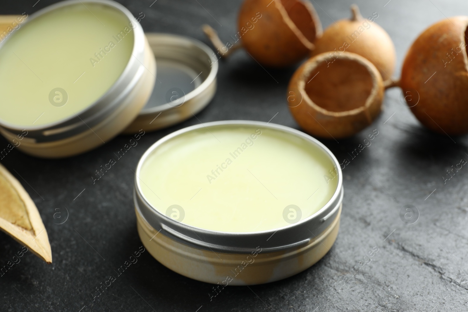 Photo of Natural solid perfume and dry fruit peels on black table, closeup