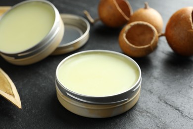 Photo of Natural solid perfume and dry fruit peels on black table, closeup